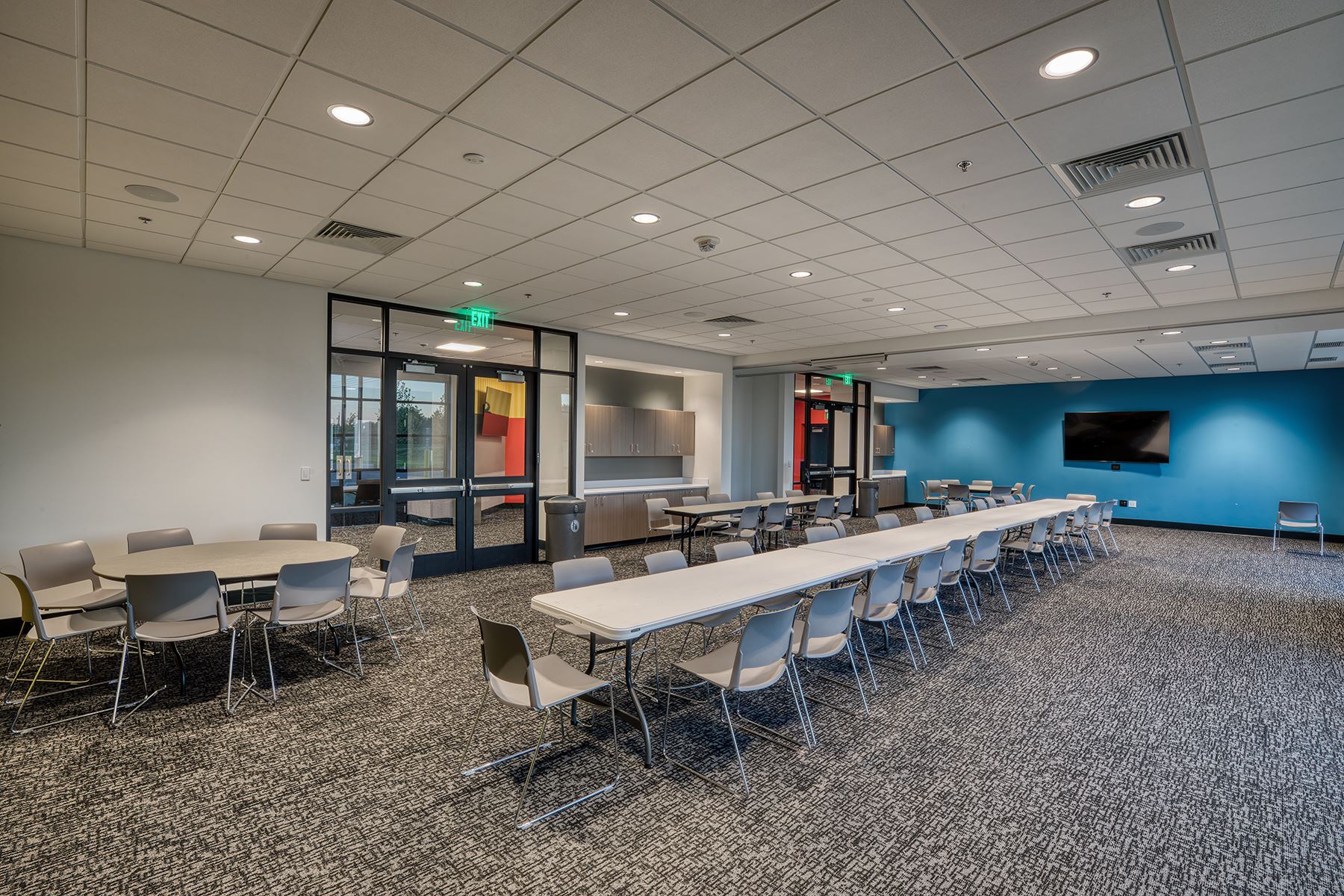 a large room with a bright blue wall set up with tables and chairs
