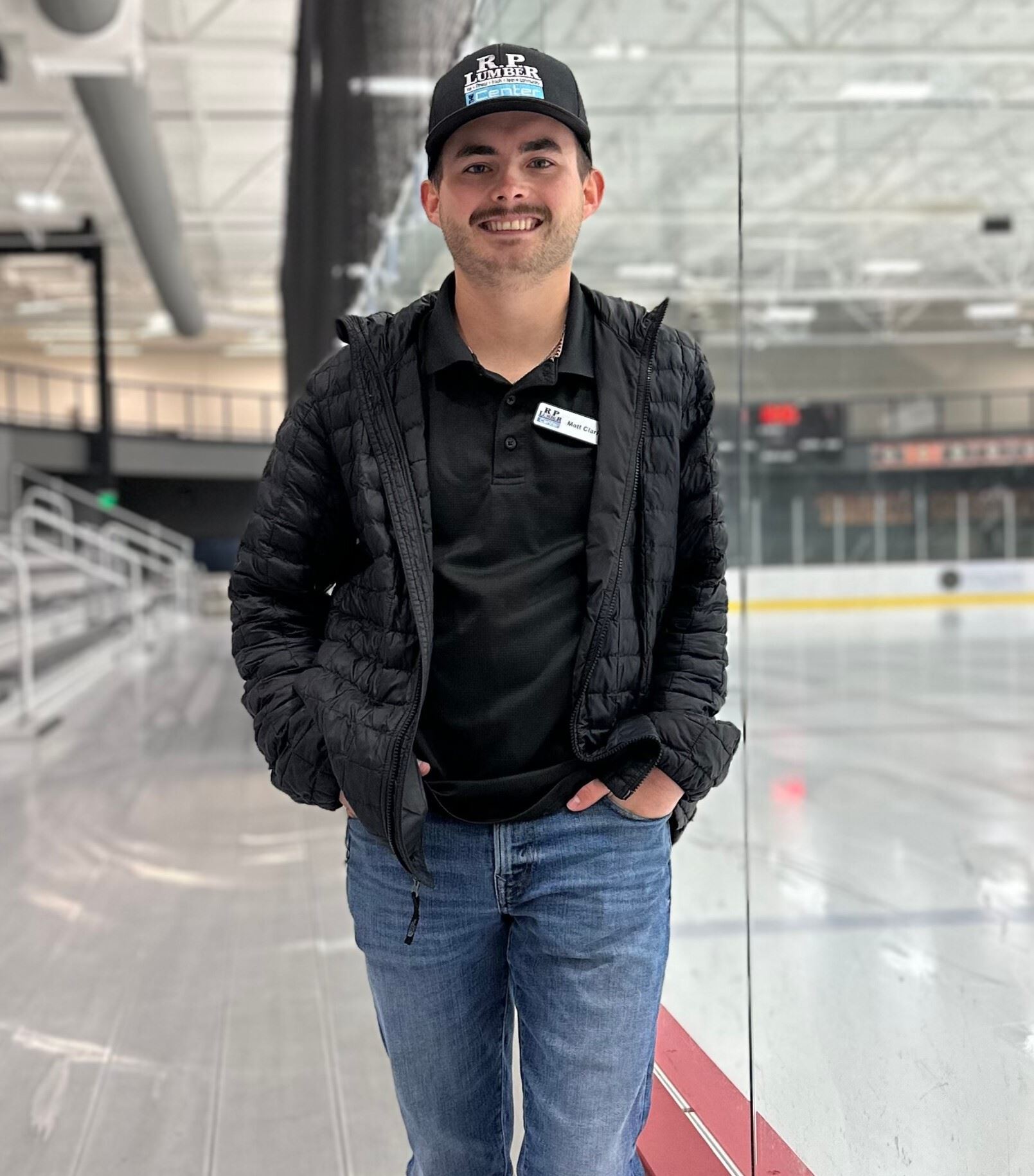 A photo of a man with a hat standing in an ice rink.